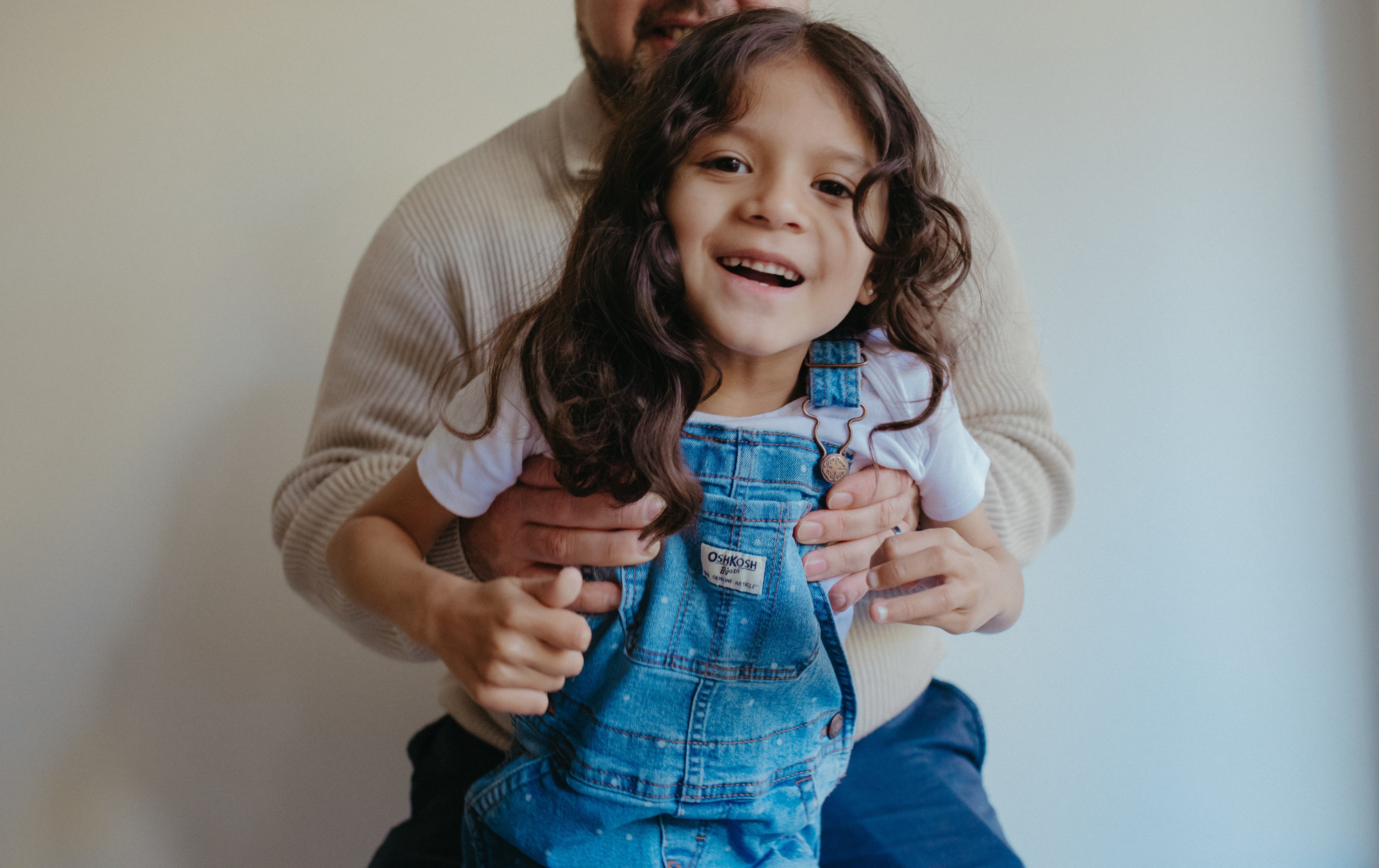 a person is holding a child in denim overalls